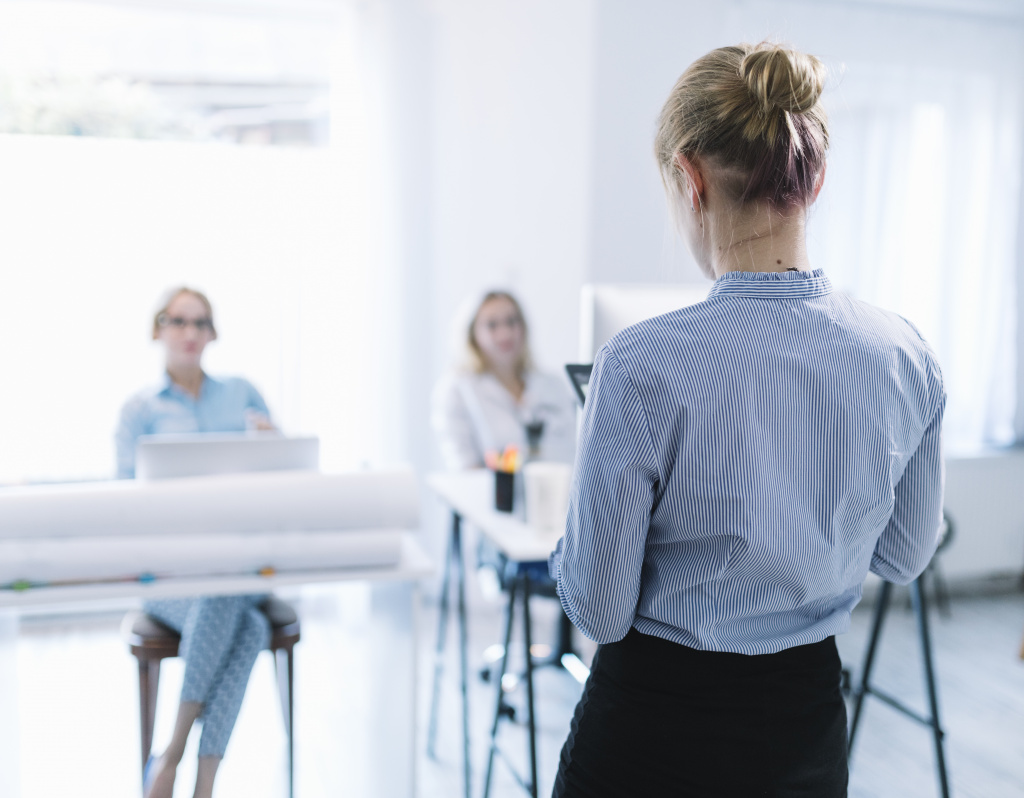 rear-view-of-a-businesswoman-giving-presentation-in-the-meeting.jpg